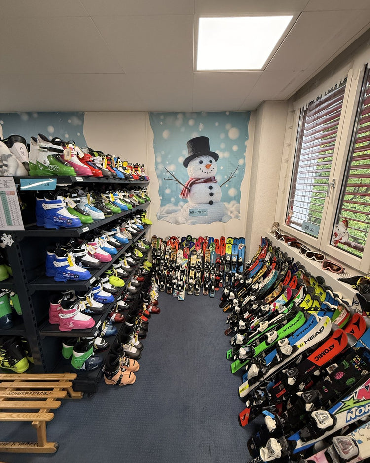 Kinderski und Skischuhe vor der Schneemann-Wand